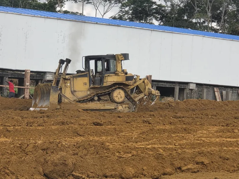 Bulldozer nivelant la plateforme le long du bâtiment